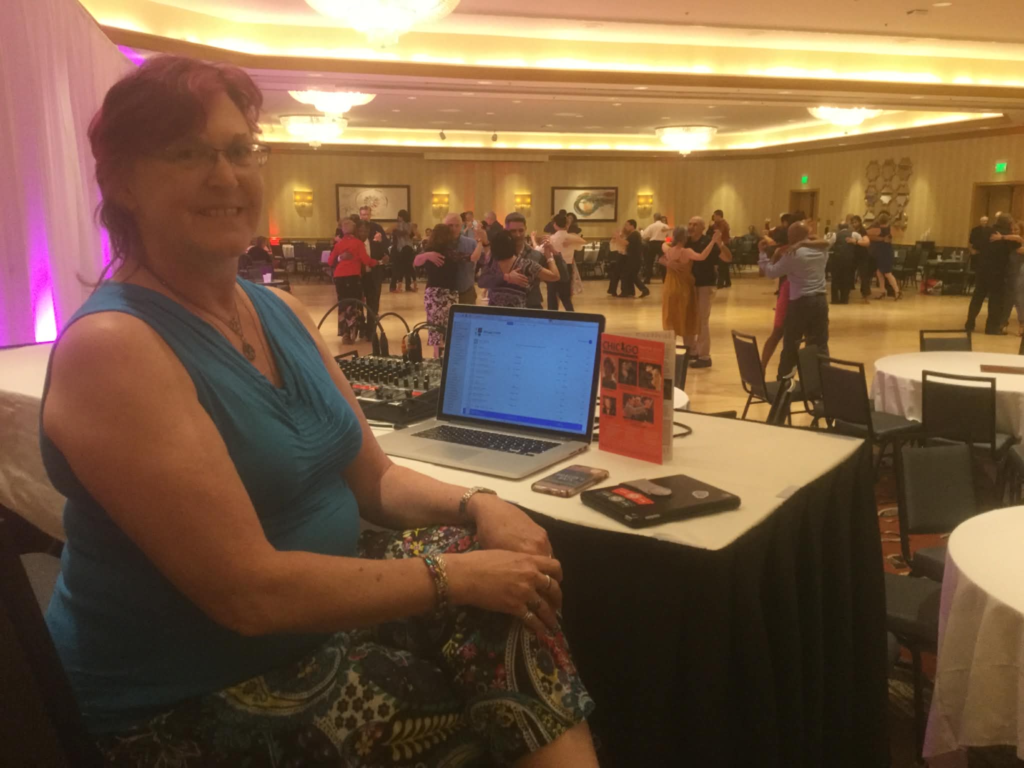 DJ Phyllis William at her DJ station with tango dancers on the floor